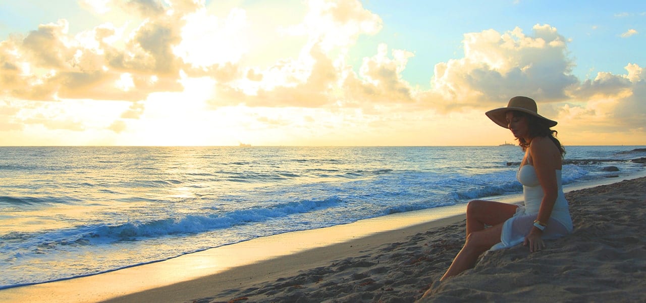 Woman sitting on a beach at sunrise in South Florida